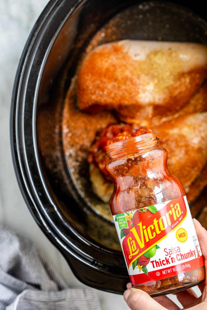 la victoria salsa poured into a crockpot with chicken