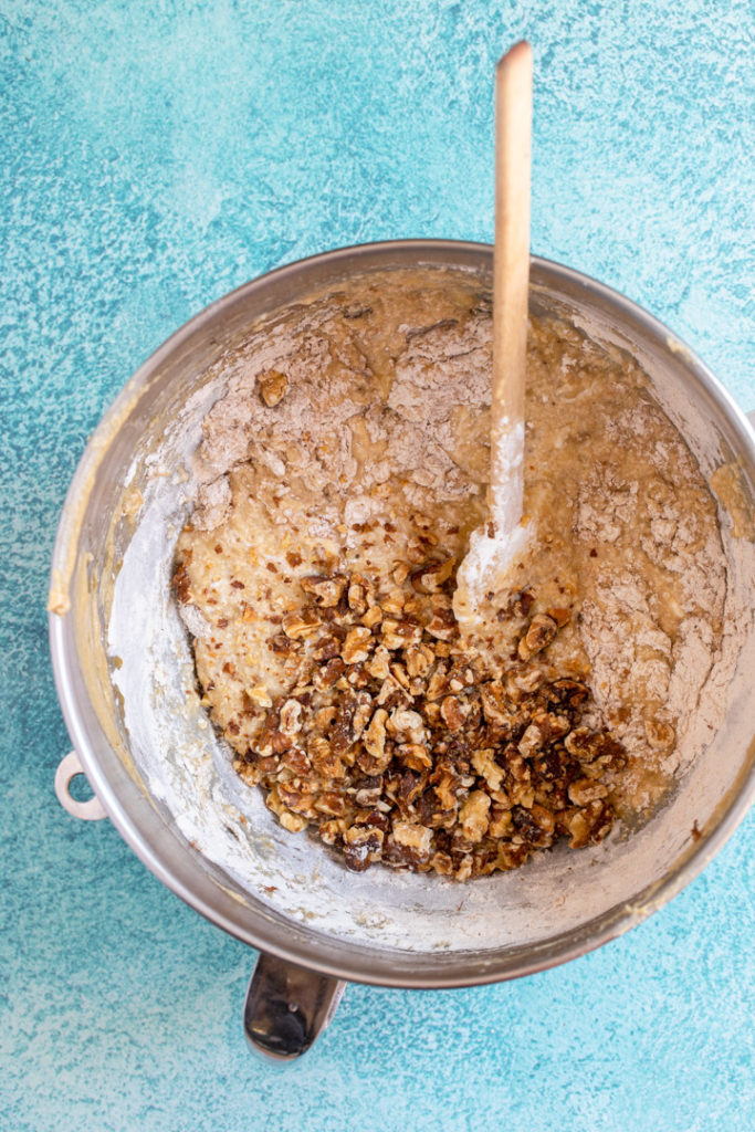 roasted walnuts added to banana bread batter in a large metla bowl