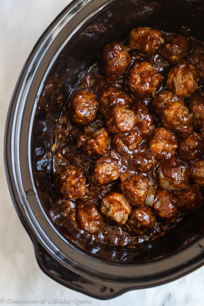 crockpot bbq meatballs in a black slow cooker dish on a white marble surface 