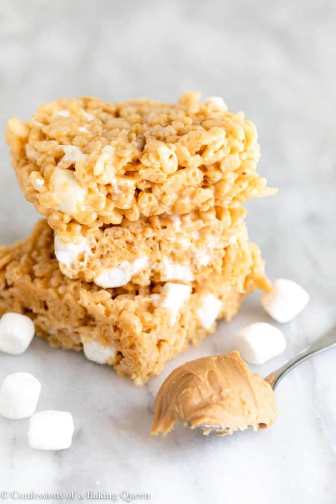 three peanut butter rice krispies stacked on top of each other next to a spoonful of peanut butter