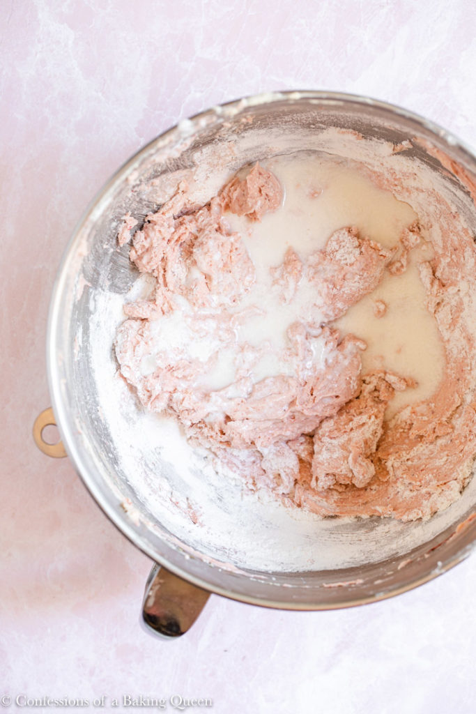 buttermilk added to strawberry cupcake batter in a large metal mixing bowl