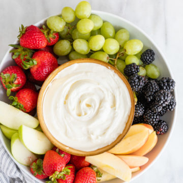 sweet cream cheese dip next to lots of fruit on a white platter