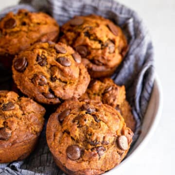 pumpkin chocolate chip muffins in a blue cloth lined bowl