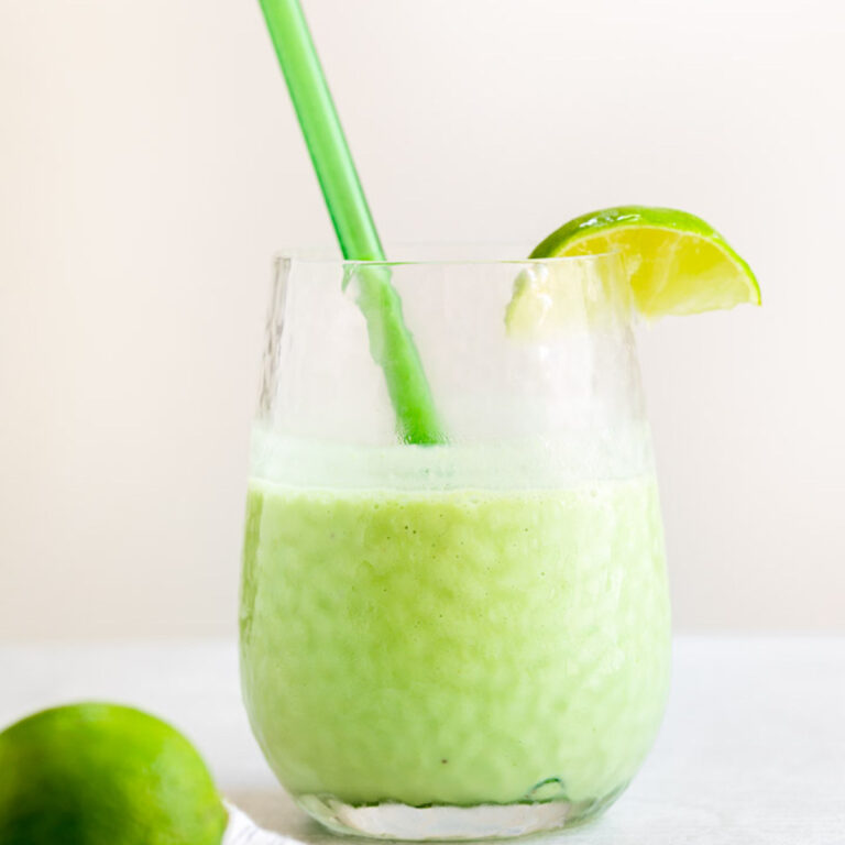 key lime smoothie in a glass with a lime wedge and green straw