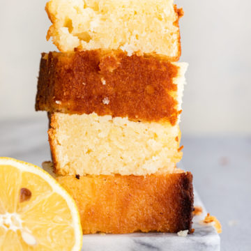 pieces of lemon pound cake stacked on top of each other on a marble surface on a grey surface