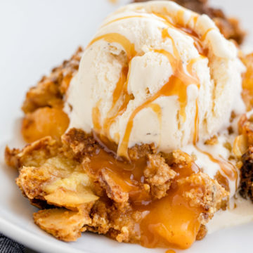 close up of peach dump cake on a white plate with ice cream