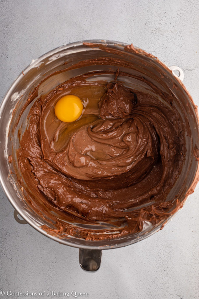 egg added to chocolate cheesecake batter in a bowl