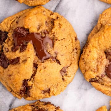chewy pumpkin chocolate chip cookie broken in half on a marble surface