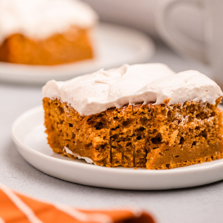 pumpkin bars with cream cheese frosting on white plates on a grey background