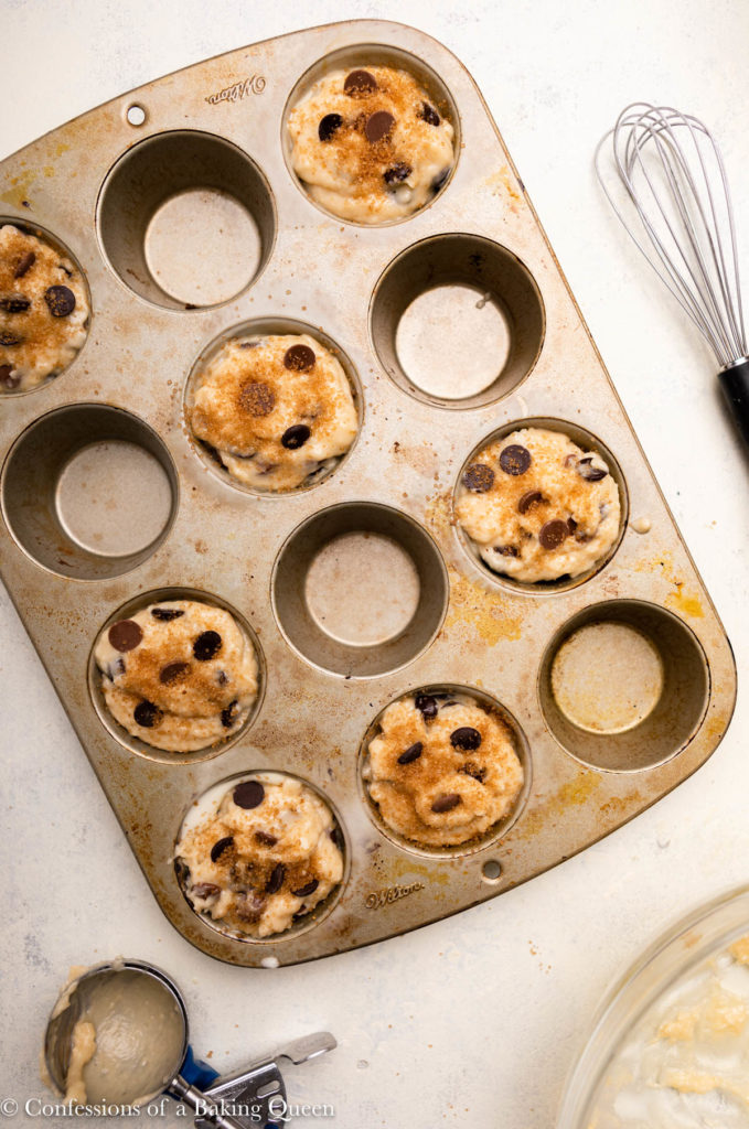 chocolate chip muffins before baking in a muffin tin with sugar on top 
