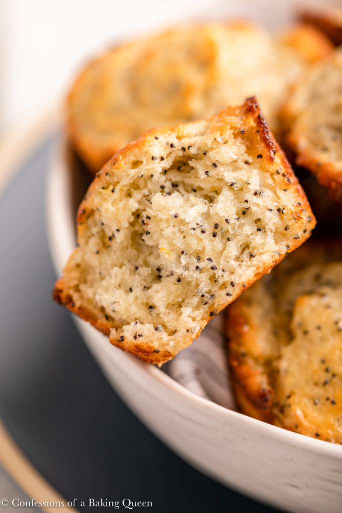 lemon poppyseed muffin half eaten in a bowl of more muffins 