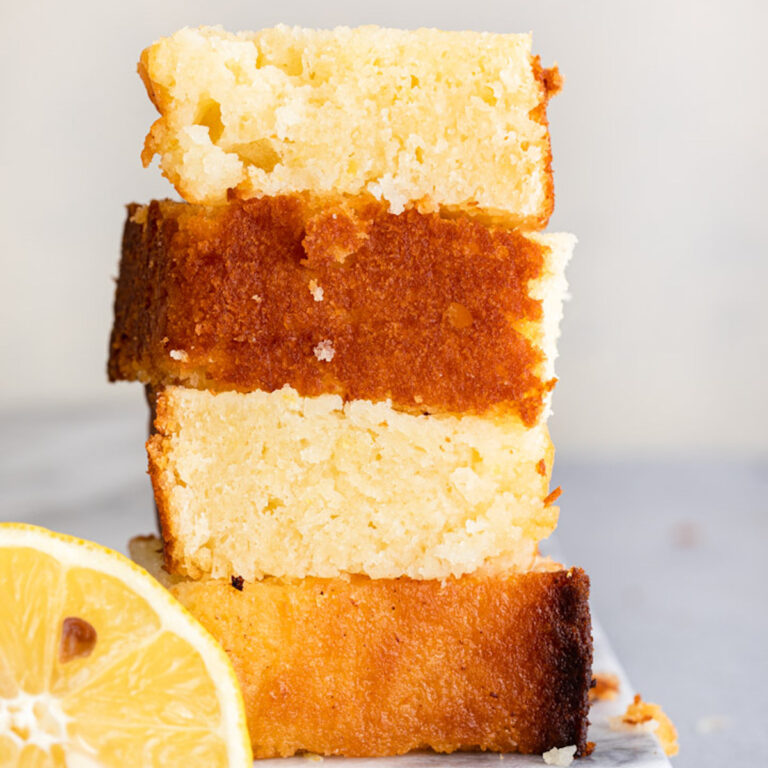 pieces of lemon pound cake stacked on top of each other on a marble surface on a grey surface