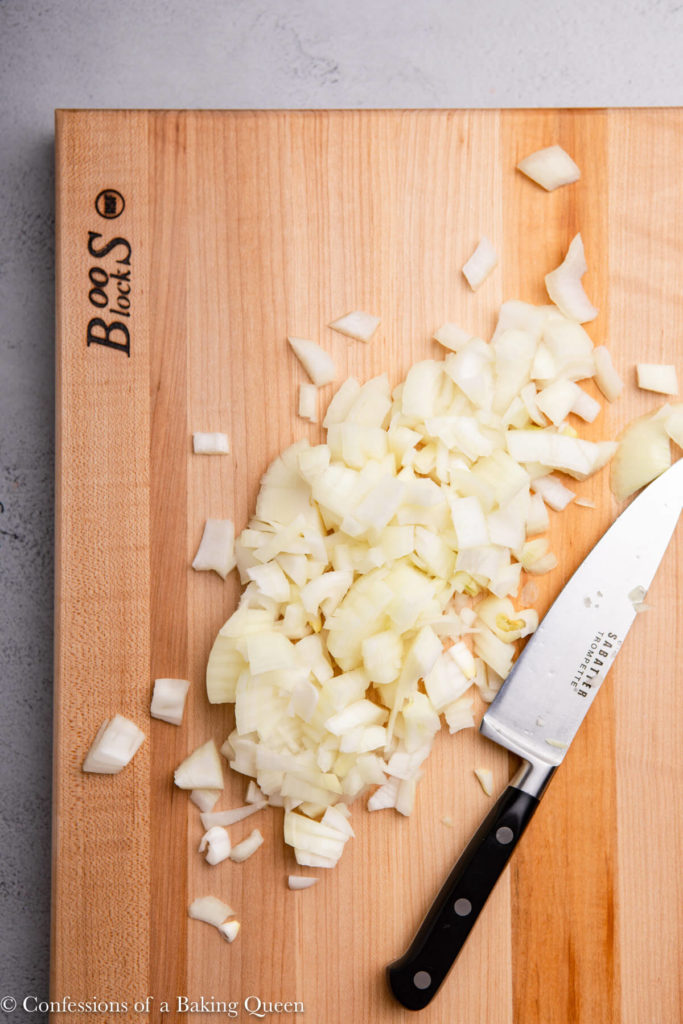 onion diced on a wood cutting board with a knife 