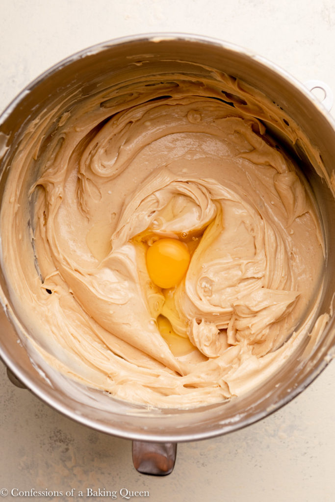 egg added to peanut butter cheesecake batter in a metal mixing bowl 