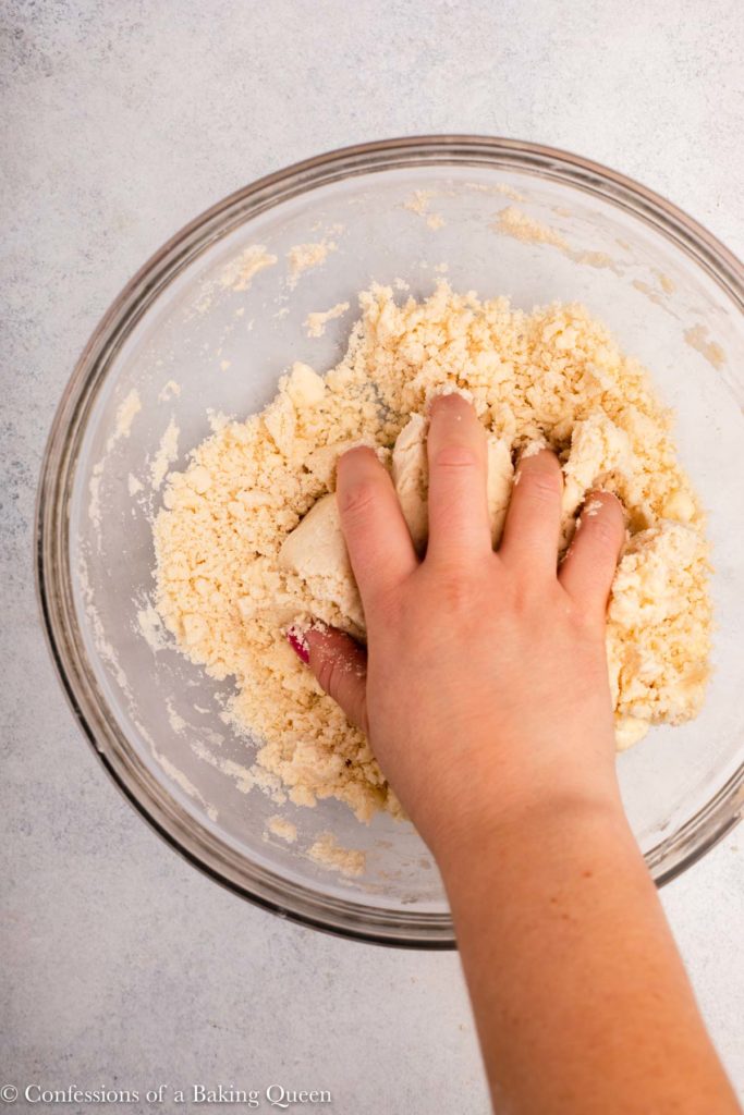 hand pressing pie crust ingredients together