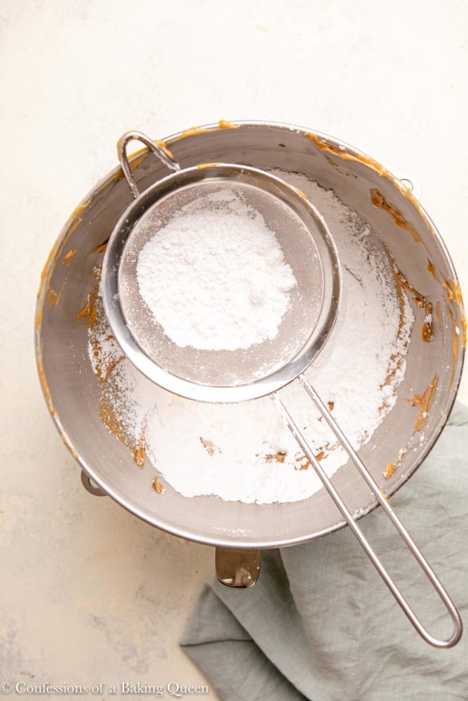 powdered sugar sifted into a bowl of peanut butter, butter, and cream