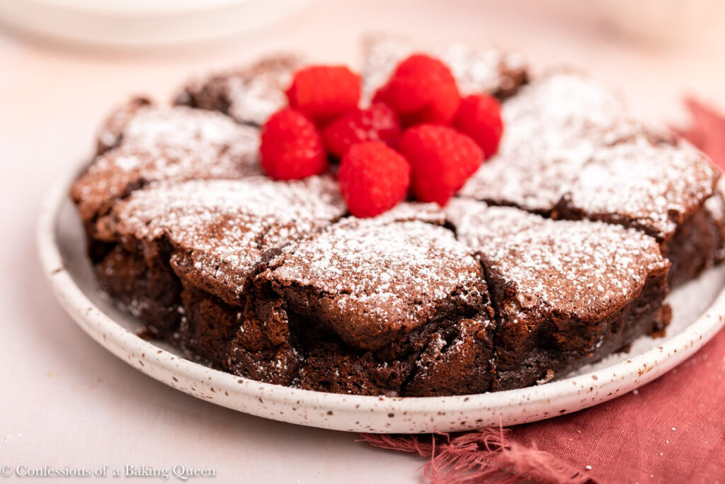 flourless chocolate cake with raspberries on a speckled plate