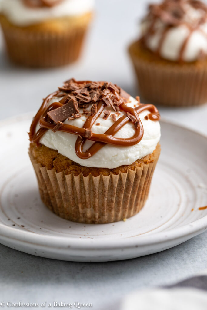 banoffee cupcake on a white plate with more cupcakes in the background on a grey surface