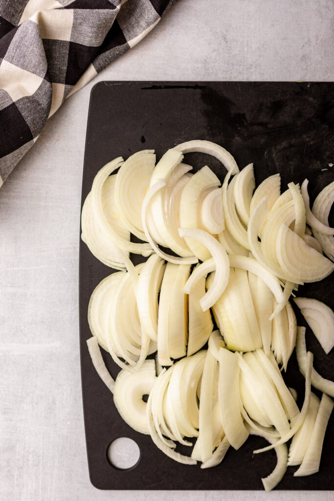 chopped onions on a black cutting board on a grey surface