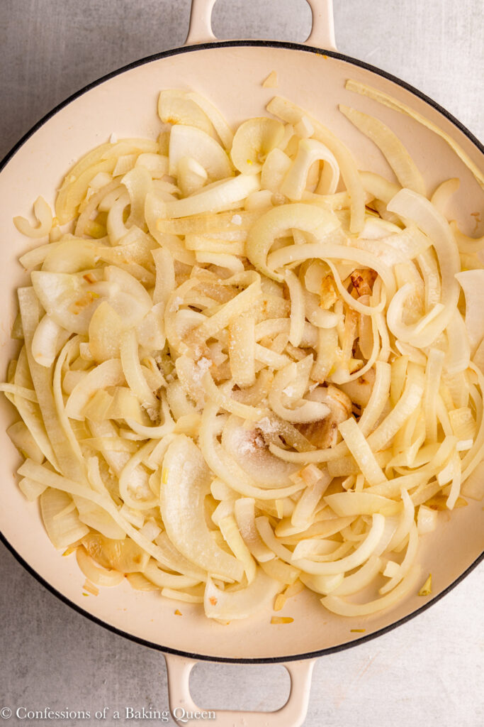 close up of onions in a white pot with some salt and sugar sprinkled on top sitting on a grey surface