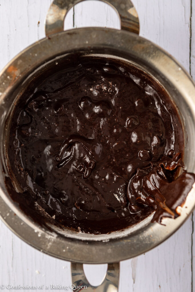 brownie batter in a metal pot on a white wood surface