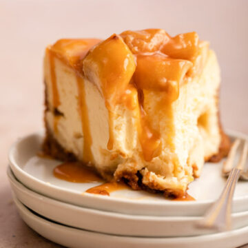 cropped-half-eaten-caramel-apple-cheesecake-slice-with-a-fork-on-a-stack-of-white-plates-on-a-light-brown-background-1-of-1.jpg