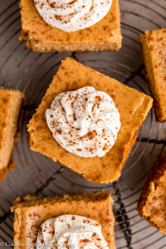 up close of pumpkin cheesecake bars on a wire rack on a brown surface 