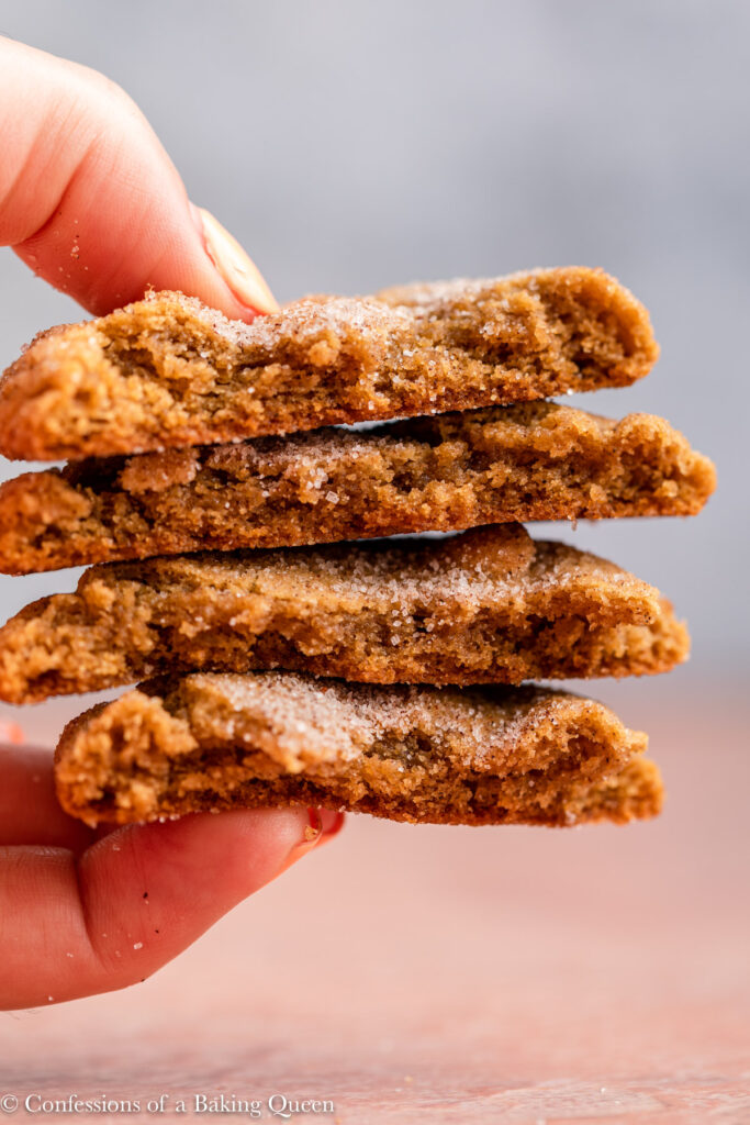 hand holding four pieces of pumpkin snickerdooles over a red and grey surface