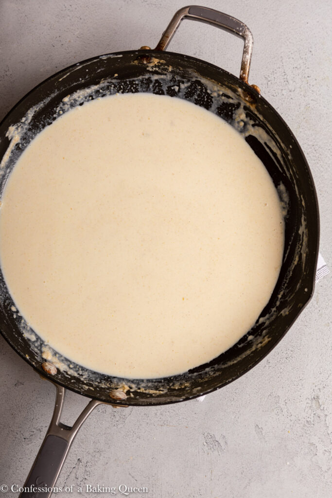 milk mixed completely into roux before thickened in a saucepan on a light grey surface
