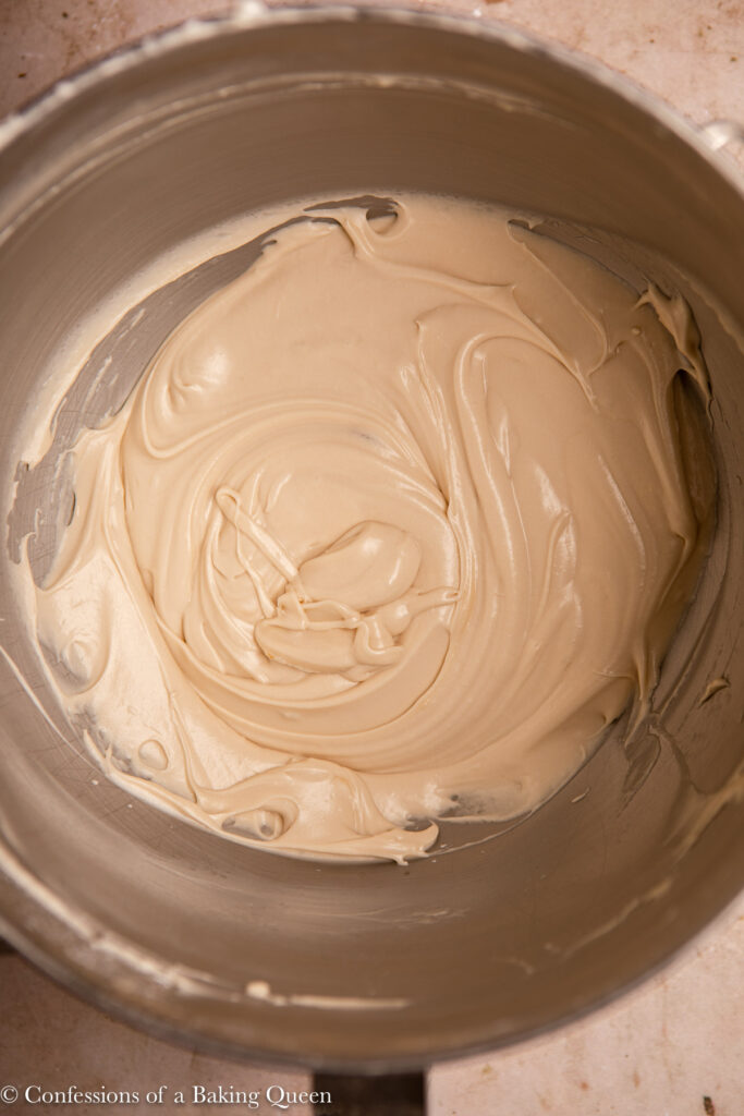 up close of maple cream cheese frosting in a metal mixing bowl