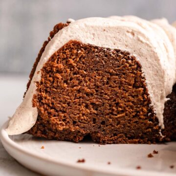 close up of sliced gingerbread bundt cake on a white plate on a light grey background