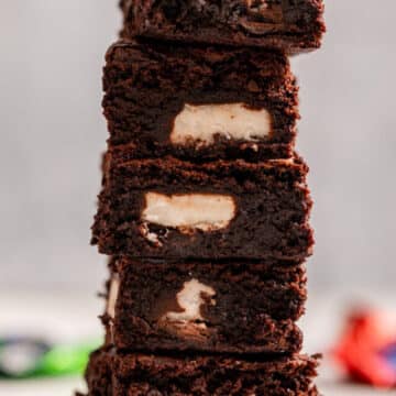 high stack of peppermint patty brownies on a light grey surface with empty candy wrappers