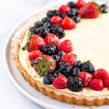 french lemon cream tart on a white plate on a white surface