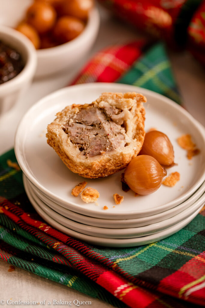 half eaten pork pie on a plate with pickled onions on a christmas linen with a christmas cracker and bowls in the background