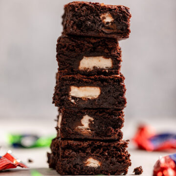 high stack of peppermint patty brownies on a light grey surface with empty candy wrappers