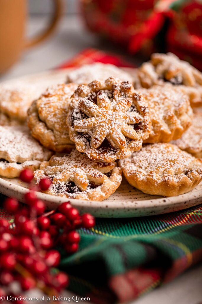 miince pies on a plate on a christmas napkin with christmas berries and a cracker in the background