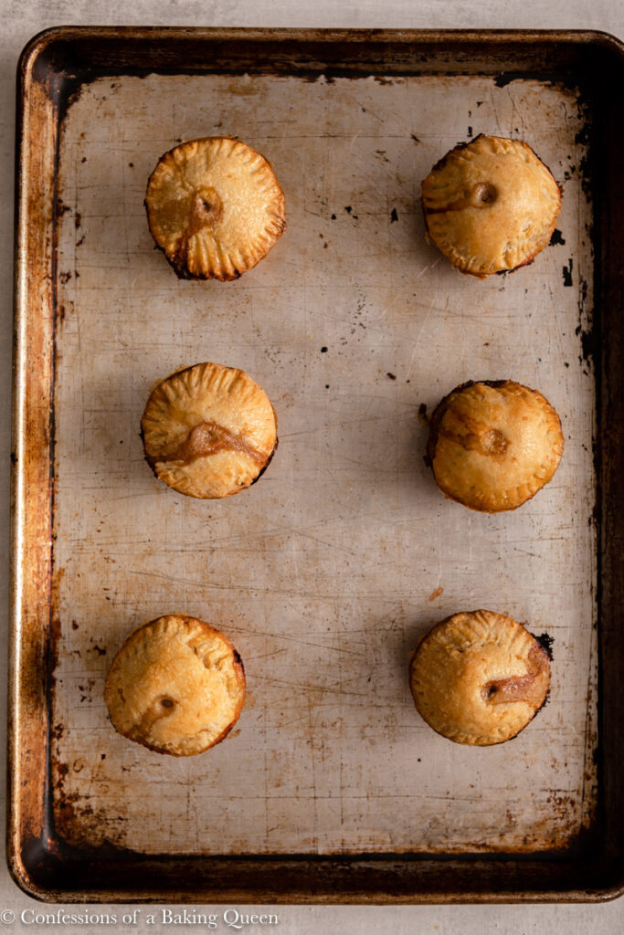 pork pies haflway baked on a sheet pan on a light grey surface