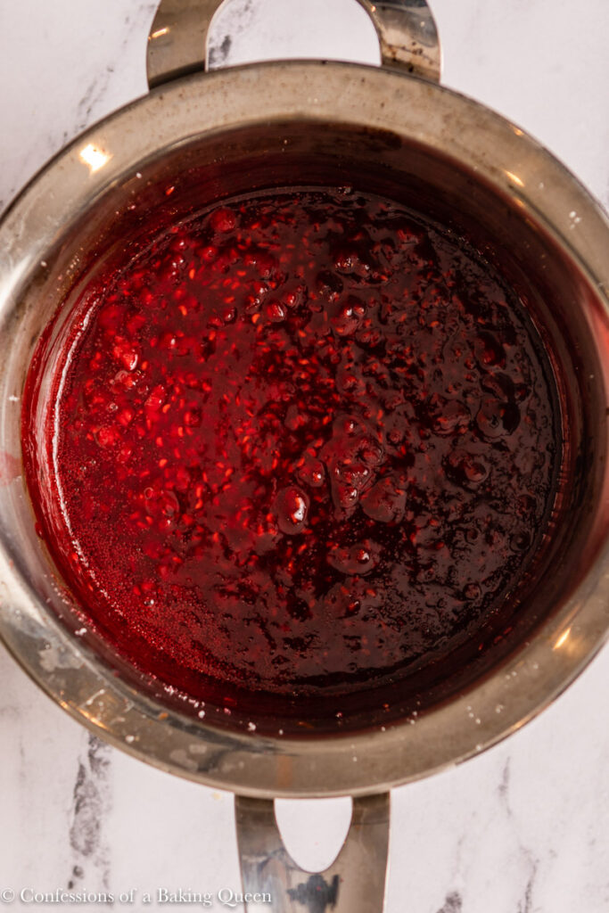 raspberry coulis cooked in a metal pot on a marble surface