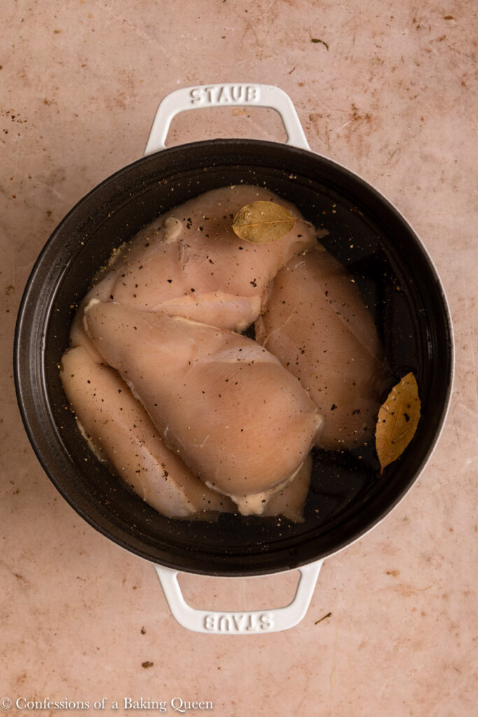 chicken breasts with spices in water in a black and white pot