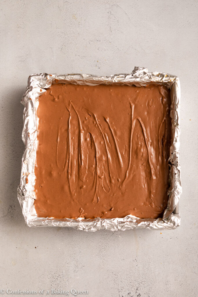 chocolate cheesecake bars before baking in a foil lined pan on a light grey surface