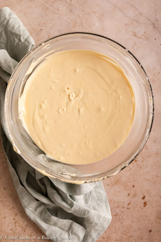 baileys cheesecake batter in a glass bowl on a light brown surface with a light green linen