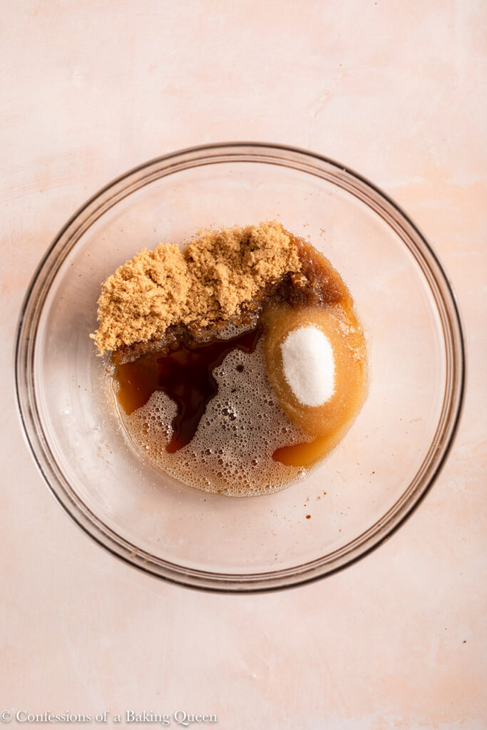 brown butter and sugars in a glass bowl on a light pink surface