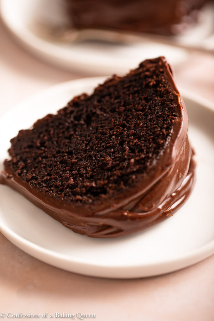 slice of chocolate bundt cake on a white plate on a light pink surface