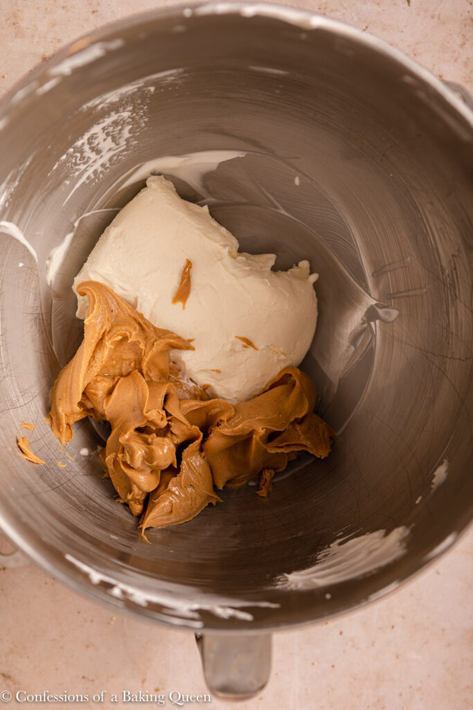 up close of cream cheese and peanut butter in a metal bowl on a light brown surface
