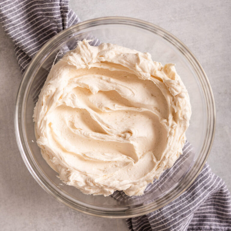 American frosting in a glass bowl on top of a blue and white linen on a light grey surface