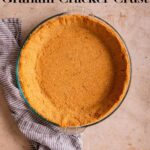 baked graham cracker crust in a glass pie dish on a light brown surface with a blue linen