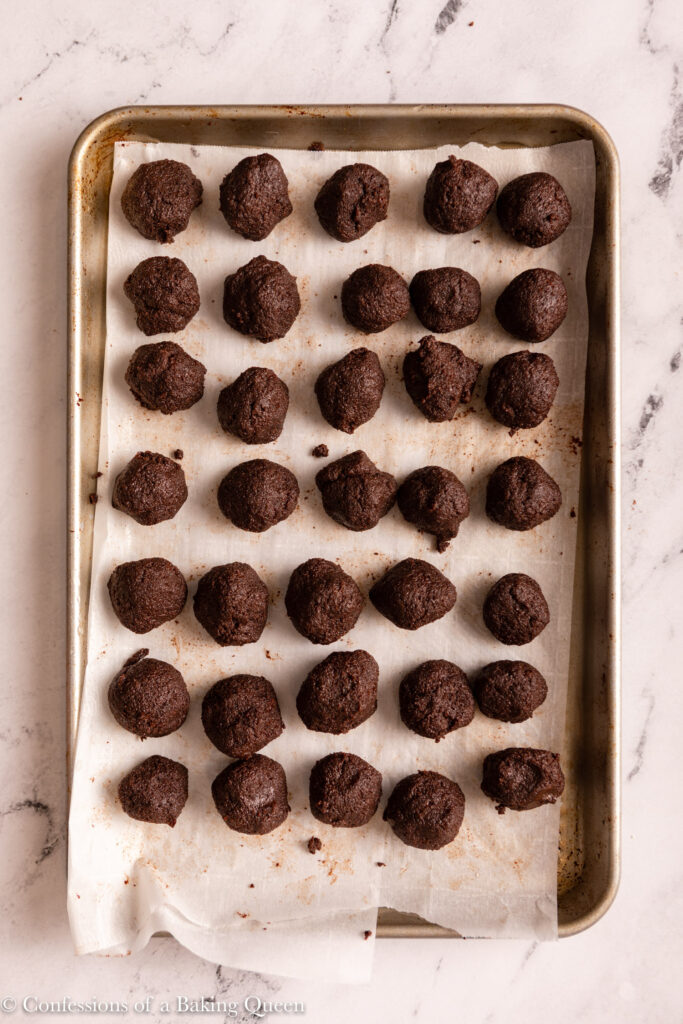 chocolate cake pop filling on a parchment lined baking sheet on a white marble surface