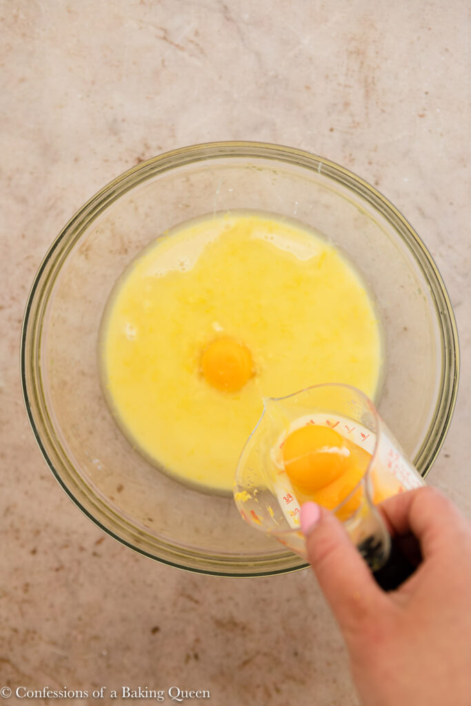 egg yolks added to lemon pie filling in a glass dish on a light brown surface