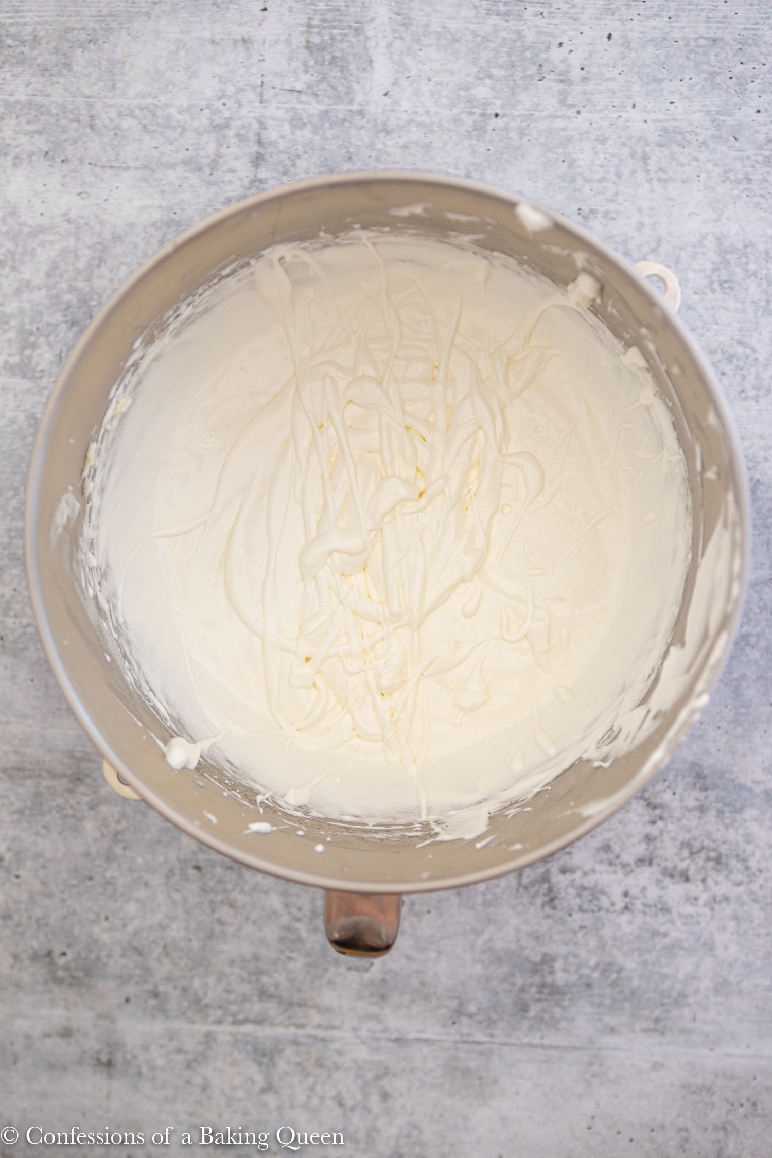 soupy Swiss meringue buttercream in a large bowl on a light grey surface