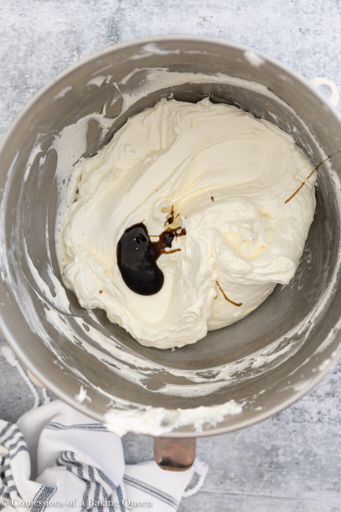 vanilla bean paste added to Swiss meringue buttercream on a light grey surface